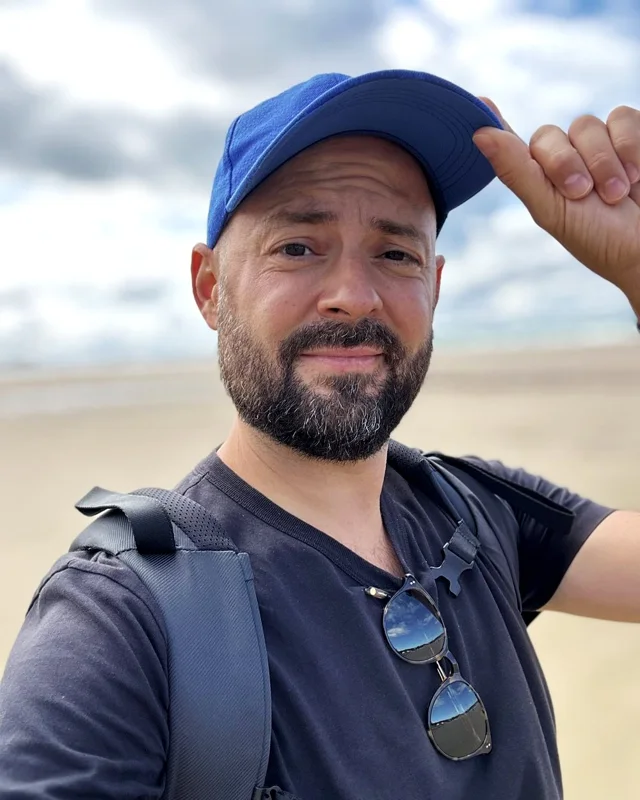 Julien Badoil à la plage, casquette bleue, qui sourit